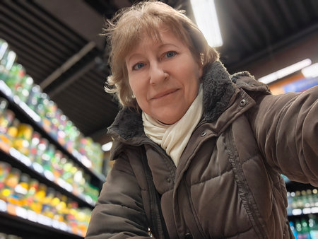 Blonde woman shares a cheerful selfie surrounded by colorful canned goods in a grocery store, showing her travel experiences and lifestyle.の写真素材