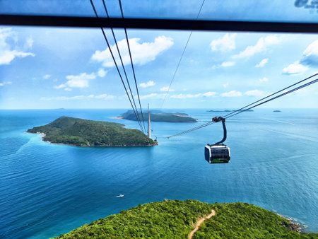 A cable car glides over clear blue waters, offering views of lush green islands on a bright sunny...