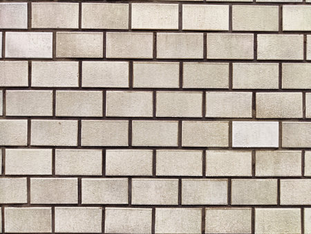 A close-up of a wall featuring rectangular concrete bricks with varied texture and subtle color...