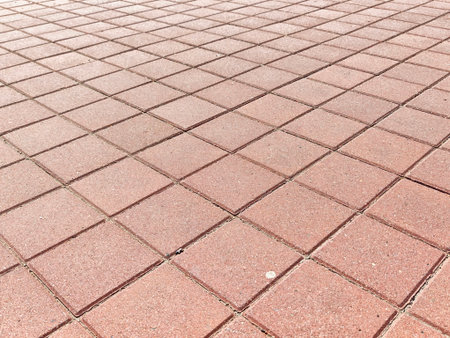 Red pavement with a distinct grid pattern offers a textured background, perfect for placing text or...