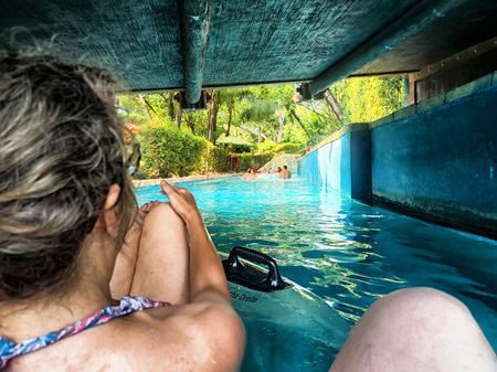 Enjoying a thrilling ride on a water slide, surrounded by vibrant greenery and friends in a serene...