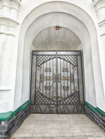 Decorative gates with ornate ironwork provide an entryway to a historic building, showing casing craftsmanship and architectural detail.の写真素材