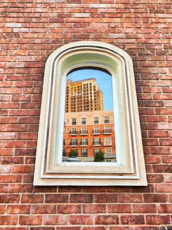 A modern building reflects in an arched window on a vintage brick wall, highlighting the blend of architectural styles in the city.の写真素材