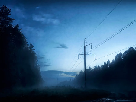 Twilight sets over a foggy landscape, with a power line stretching through a serene forested area...