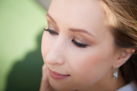 Close-up of a woman with elegant makeup enjoying a sunny afternoonの写真素材