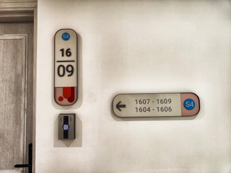 Directional signs indicate room numbers 1607 to 1609 and 1604 to 1606 in a contemporary hotel hallway with a sleek design.の写真素材