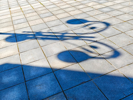 Shadows of musical notes dance across a patterned pavement, showcasing artistic expression in the midday sun at a community gathering space.の写真素材