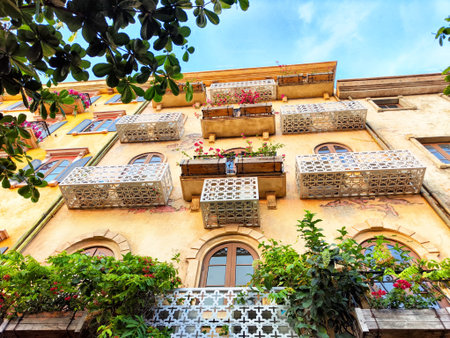 Colorful flower-filled balconies create a lively atmosphere on this charming building in a historic urban setting.の写真素材