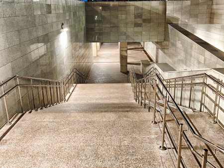 Illuminated underground pedestrian passage with stairs and metal railings in Kazan, Russia at nightの写真素材