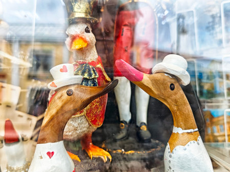 Handcrafted wooden ducks adorned with hats and heart designs interact with a bright penguin, showcasing whimsical wedding decor in a shop.の写真素材