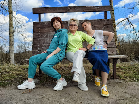Three friends enjoying a sunny day on a park bench amidst a scenic backdrop of blue skies and clouds