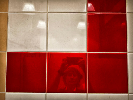 Bright red and white tiles enhance the visual appeal of a contemporary wall, with a reflection capturing a moment.の写真素材