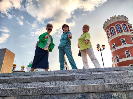 Friends enjoying a sunny day at a historical site, posing playfully on steps with a beautiful backdrop in the early eveningの写真素材