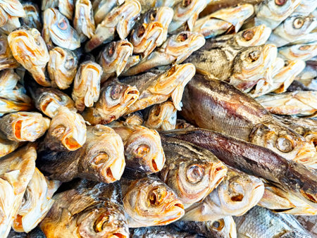 Freshly caught fish are laid out for sale at a bustling market, with vendors promoting their dried fish selection in the sunlight.の写真素材