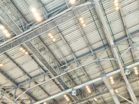 Bright ceiling with metal beams and lights highlights the spacious design of an industrial space, emphasizing its modern architecture.の写真素材