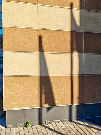 A flag's shadow displays on a brown textured wall, captured in the afternoon light near a city environment.の写真素材