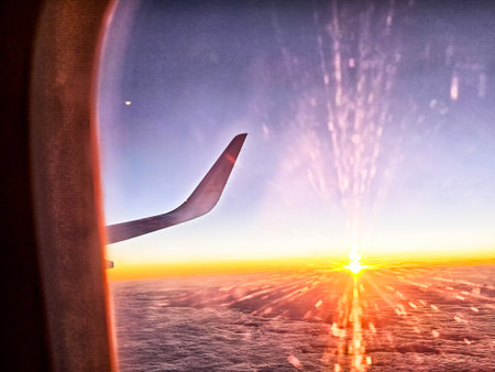 A beautiful sunset lights up the sky as seen from an airplane window, with the aircraft wing visible...