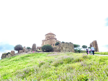 People walk through vibrant wildflowers while visiting scenic ruins and a historical church on a...