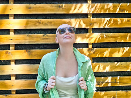 Bald girl smiling confidently after overcoming cancer, embracing life in recoveryの写真素材