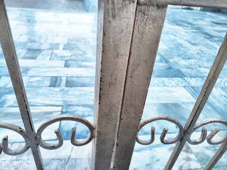 A weathered metal gate reveals a tranquil courtyard with blue tiles, glowing under the warm...