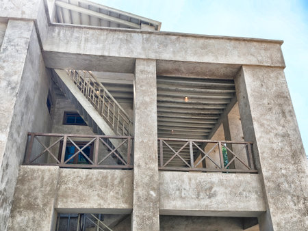A concrete building showcases a staircase leading to the upper level, surrounded by a bright, clear...