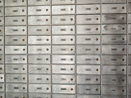 Rows of metal mailboxes are displayed against a wall, each with a number indicating its unique slot,...