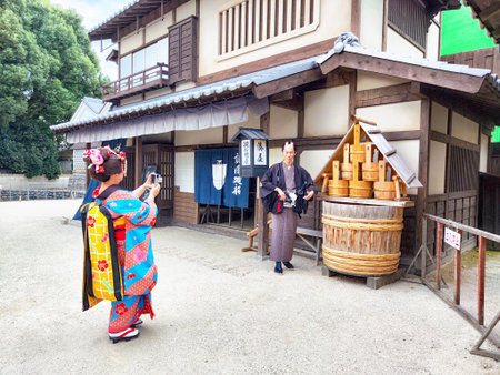 Kyoto, Japan - October 27, 2024: Visitors enjoy TOEI Kyoto Studio Park while wearing traditional clothing and taking photos near historic buildings in Kyoto.のeditorial素材
