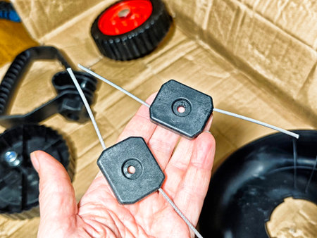 Replacement parts for outdoor equipment are displayed in a hand against a wooden background, showing tools and accessories organized nearby.の写真素材