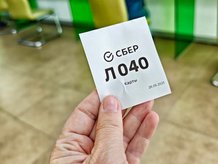 Kirov, Russia - August 26, 2025: A ticket is held in hand showing number L040 for service processing at a financial institution on March 26, 2025.のeditorial素材