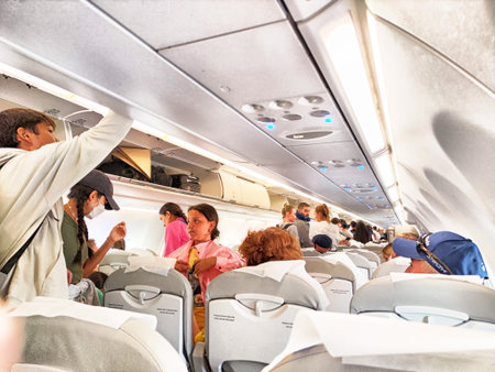 Tashkent, Uzbekistan - April 09, 2025: Travelers gather inside the aircraft cabin, preparing for their journey to Tashkent, Uzbekistan, amid a bustling atmosphere.のeditorial素材