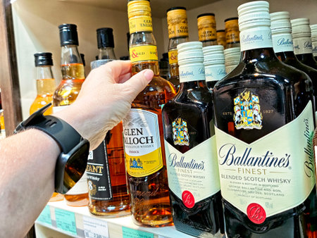 Maikop, Russia - June 04, 2025: A hand reaches for a bottle of Glen Talloch whiskey among several options on a store shelf in Maikop, showing a variety of spirits available.のeditorial素材