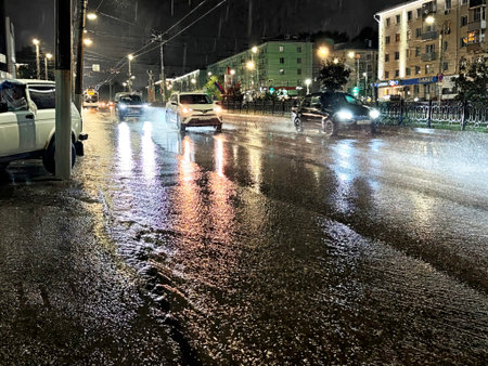 Kirov, Russia - August 30, 2025: Vehicles navigate a slick road reflecting colorful lights on a rainy night, creating a vibrant yet moody atmosphere.のeditorial素材
