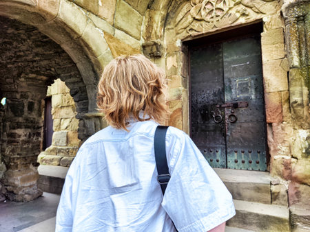 A visitor stands before an ancient castle door, admiring the intricate stonework and aged wood. The scene captures a moment of discovery.の写真素材