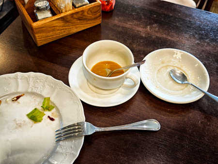 Leftover food and drinks sit on a table after a meal, showing a busy brunch scene in a cozy cafe with wooden decor.の写真素材