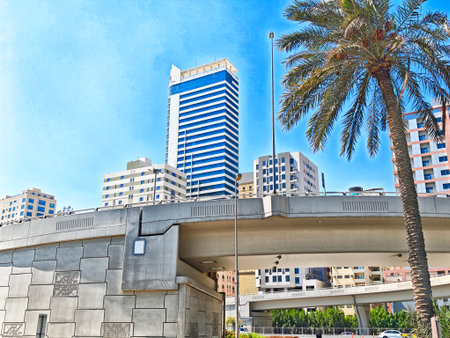 Bright blue skies highlight the skyline of Manama, Bahrain, showcasing tall buildings and palm trees along a busy road.の写真素材