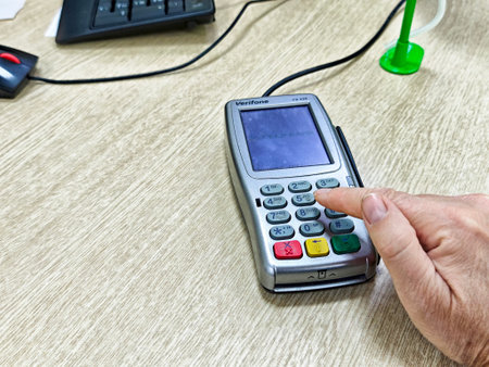Kirov, Russia - August 26, 2025: A person is entering information on a card reader device at a bank,...