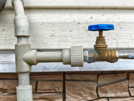 Detailed view of a plumbing valve and pipes arranged for water flow management at a residential property during the day.の写真素材