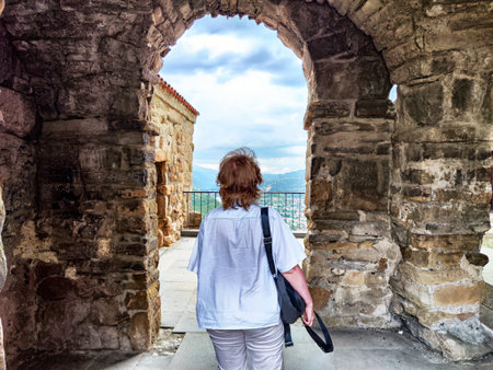 A person strolls through an ancient archway, enjoying beautiful views of the landscape and city...