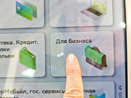 Kirov, Russia - August 26, 2025: User points at business services on a digital kiosk screen in a...