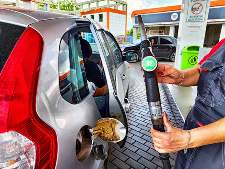 Kirov, Russia - June 12, 2025: A person fills a car with fuel at a gas station while another person...