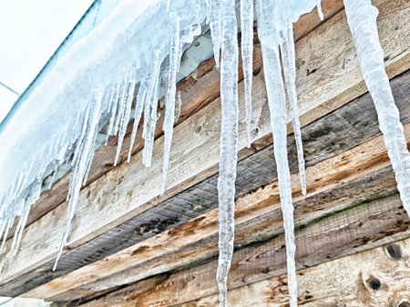 Long icicles hang from the roof edge, showing winter hazards and the need for proper maintenance to...
