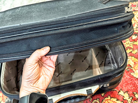 Kirov, Russia - November 14, 2025: A hand holds a worn bag in a simple home setting, highlighting the everyday items that support a functional and modest lifestyle.のeditorial素材