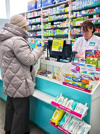 Kirov, Russia - December 14, 2025: Customers buy medicines and consult with the pharmacist at the drugstore counter in a healthcare retail service.のeditorial素材