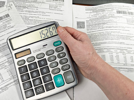 Kirov, Russia - December 29, 2025: A person uses a calculator to add up monthly expenses while...
