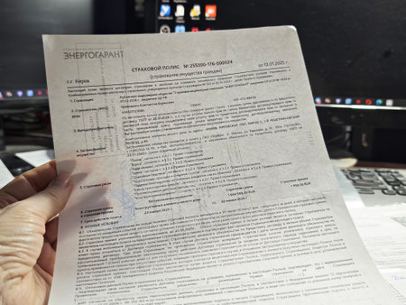 Kirov, Russia - January 04, 2026: Mortgage insurance or loan agreement documents held by person at home desk. Financial paperwork concept showing household obligations, planning and responsibilityのeditorial素材