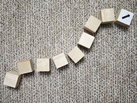 Wooden blocks are laid out in a sequence showing an upward trend on a surface, symbolizing business...