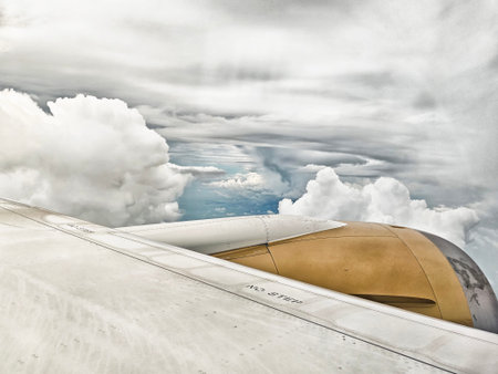 Clouds can be seen outside an airplane window while flying over the ocean. The wing and engine are...