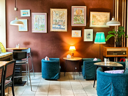 Kirov, Russia - November 05, 2025: Seating in a cafe includes blue chairs and small tables with art on the walls and low lighting creating a relaxed atmosphere.のeditorial素材