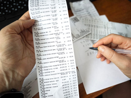 Kirov, Russia - January 05, 2025: Calculator with grocery receipts and handwritten expense calculations on paper, symbolizing budgeting, cost calculation, personal finance planning, and home accountingのeditorial素材