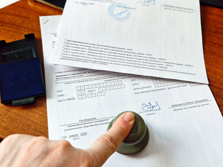 Kirov, Russia - January 14, 2026: A company stamp is pressed onto official documents on a desk, showing the process of business approval and compliance in an office.のeditorial素材